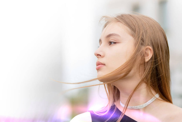 Eine schöne Frau im Profil mit fliegenden Haarsträhnen vor einem Bokeh-Hintergrund. Porträt eines jungen romantischen Mädchens. - Foto, Bild