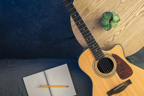 Guitarra acústica e bloco de notas com lápis na mesa, vista superior. Fundo musical, conceito de ensaio, aprender a tocar guitarra. Espaço de cópia. - Foto, Imagem