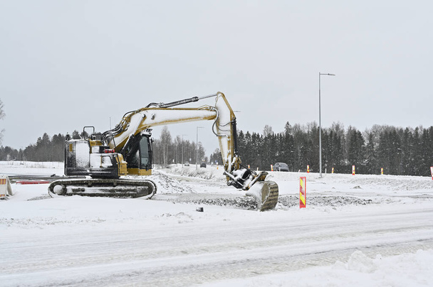 Ein Bagger arbeitet inmitten einer verschneiten Landschaft, räumt Schnee oder ist mit Bauarbeiten beschäftigt - Foto, Bild