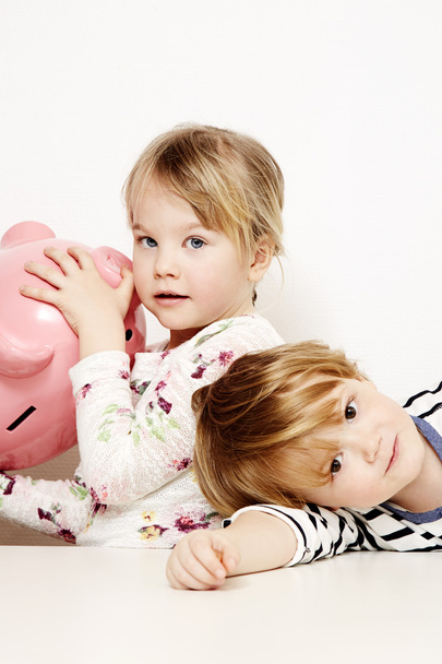 Brother and sister holding piggy bank - Foto, afbeelding