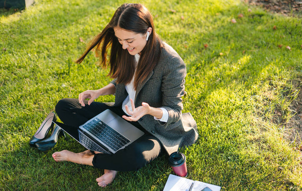 Stylowa kobieta przedsiębiorca pracuje z nowoczesnym, kabrioletowym laptopem odkrytym jesienią w parku miejskim. Młoda profesjonalistka na zewnątrz za pomocą laptopa - Zdjęcie, obraz