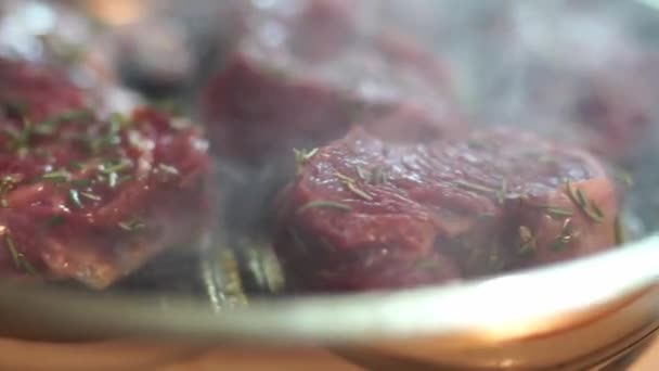 Una persona está cocinando carne roja en una sartén con un tenedor. El plato puede consistir en carne de cerdo o de res, y se está preparando como parte de una receta con productos animales - Metraje, vídeo