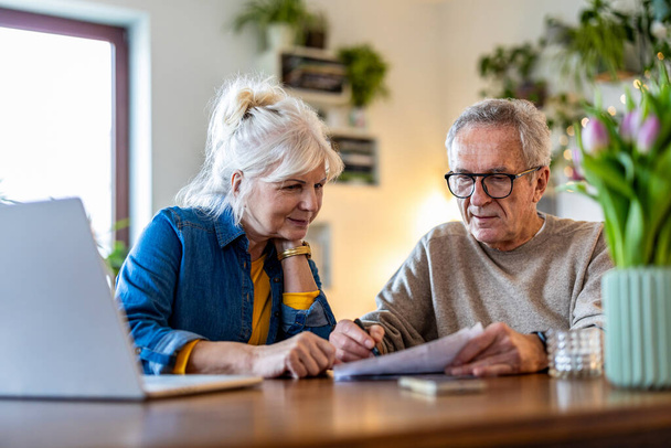 Seniorenpaar sitzt am Tisch und diskutiert über Hausfinanzen - Foto, Bild