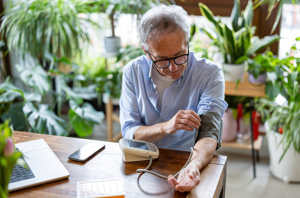 Homme âgé mesurant la pression artérielle à la maison
 - Photo, image