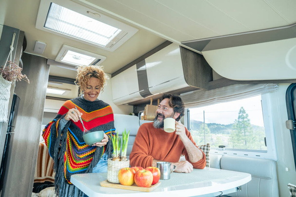  mature couple enjoy life in a camper van motorhome together in indoor leisure activity. Nature view outside the window. Happy traveler people man and woman inside a van for vacation holiday - Foto, Imagem