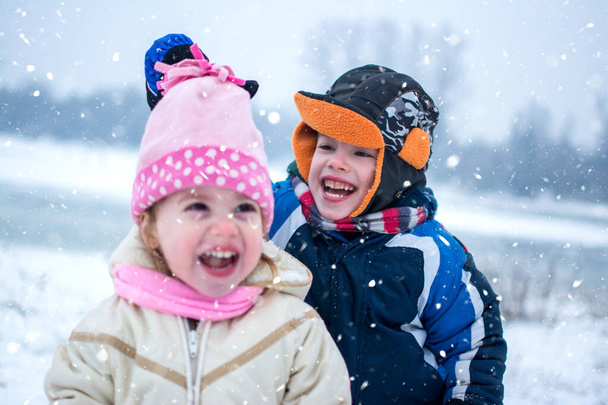 Веселые дети играют вместе в снежный зимний день - Фото, изображение