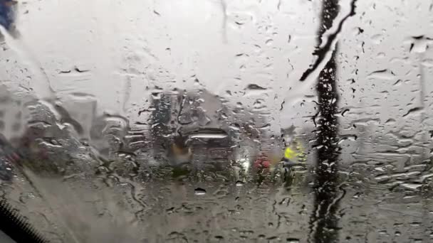 Gouttes de pluie sur la fenêtre de la voiture avec fond trouble de rues de la ville fond sur le jour de pluie en hiver avec éclaboussures et gouttes de pluie goutte à goutte ondulation dramatique dans l'orage et de fortes pluies sur la fenêtre de la voiture - Séquence, vidéo