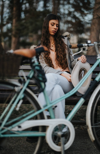 Mujer de negocios disfrutando de un momento de tranquilidad mientras se sienta con su bicicleta en un entorno tranquilo parque - Foto, Imagen