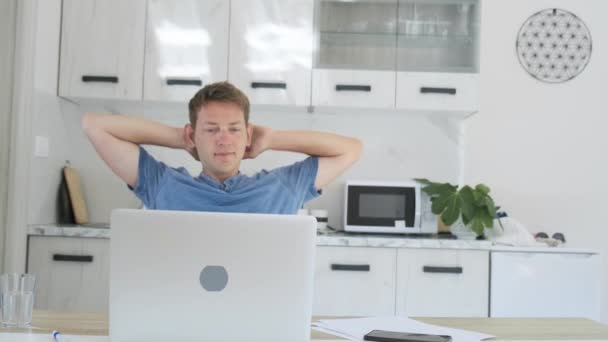 Spokojeně pohledný muž na volné noze práci na notebooku doma dává ruce za hlavu a šťastný s dobře odvedenou prací. Mužský podnikatel relaxovat po náročném pracovním dni dokončena projektová práce na počítači. - Záběry, video