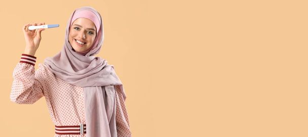 Happy muslim žena s těhotenským testem na béžové pozadí s prostorem pro text - Fotografie, Obrázek