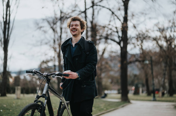 Стильний молодий дорослий, що стоїть з велосипедом на безтурботній парковій доріжці, з деревами і чистим небом на задньому плані. - Фото, зображення