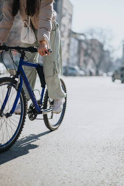 Nuori nainen nauttii rauhassa pyöräilystä kirkkaana, aurinkoisena päivänä kaupunkiympäristössä, jossa on aktiivinen elämäntapa. - Valokuva, kuva
