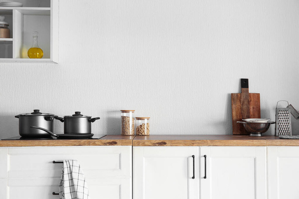 Деревянная столешница с кастрюлями на электрической плите на современной кухне - Фото, изображение