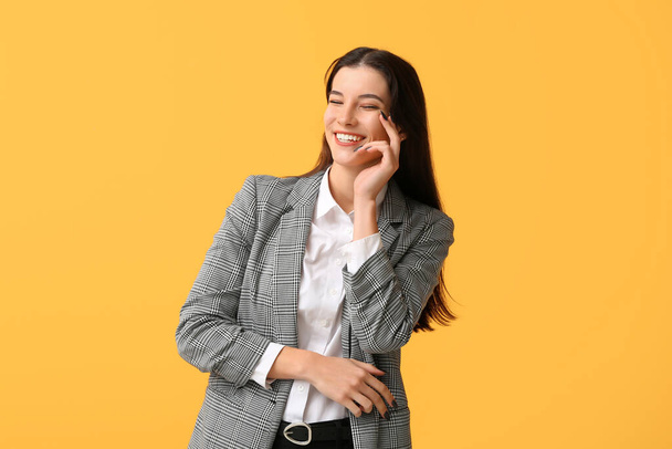 Hermosa joven empresaria feliz riendo sobre fondo amarillo - Foto, imagen