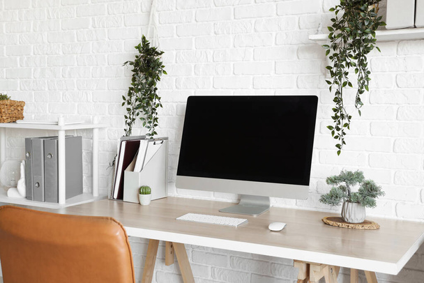 Blank computer monitor with plants on table in light office - Photo, Image