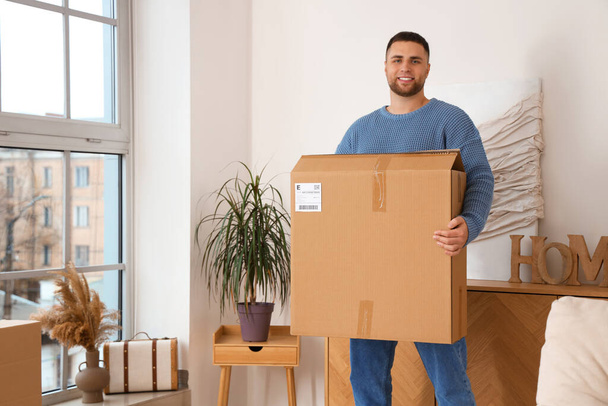 Молодой человек с большой коробкой посылок дома - Фото, изображение