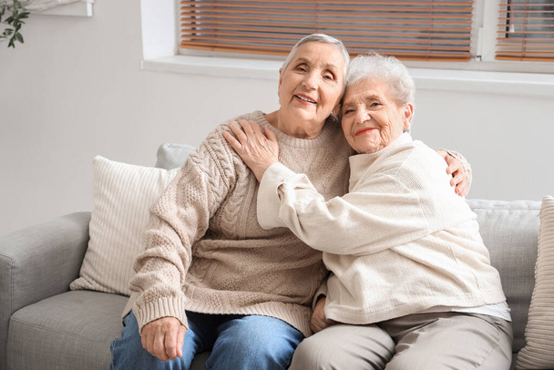 Старші друзі-жінки обіймаються на дивані вдома - Фото, зображення