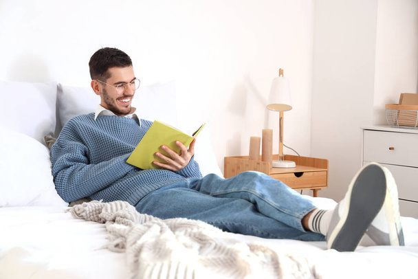 Молодой человек читает книгу в спальне - Фото, изображение