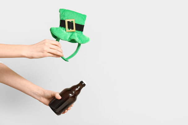 Mani con birra e decorazioni per feste a forma di cappello da folletto su sfondo chiaro. Festa di San Patrizio - Foto, immagini