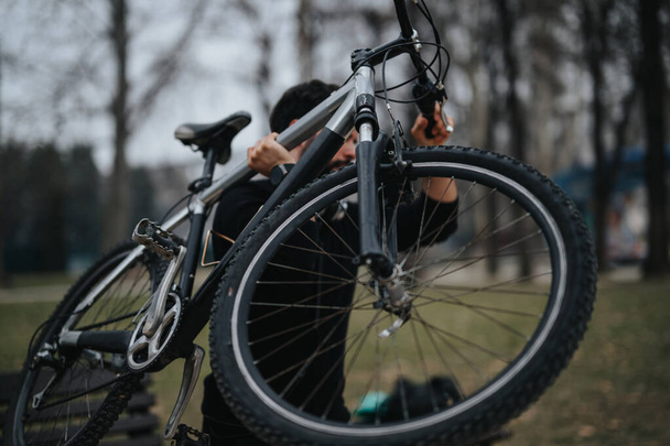 Konzentrierter Geschäftsmann, der eine entspannte Fahrradtour in einer ruhigen Parklandschaft unternimmt und einen aktiven Lebensstil pflegt. - Foto, Bild