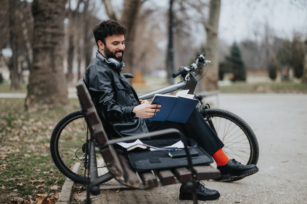 Homme d'affaires élégant aime travailler à distance du parc, en utilisant un téléphone et un ordinateur portable avec son vélo à proximité. - Photo, image