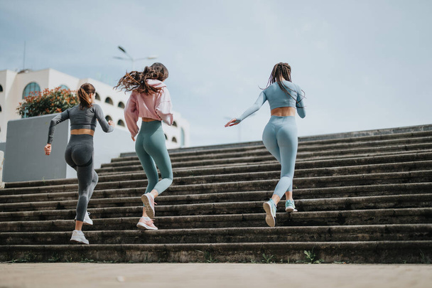 Aktive junge Freunde in Trainingsausrüstung joggen in urbaner Umgebung Stufen hinauf und trainieren für Gesundheit und Fitness - Foto, Bild