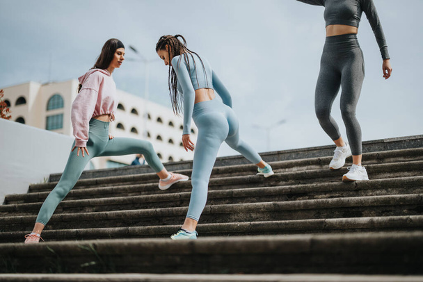 Şehir merdivenlerinde spor yapan bir grup bayan arkadaş, takım çalışması ve sağlıklı bir yaşam tarzı sergiliyorlar.. - Fotoğraf, Görsel