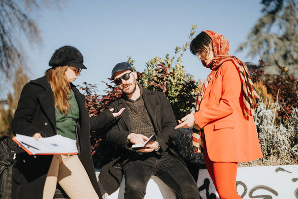 Gruppe multikultureller Unternehmer bei einem Treffen im Freien, umgeben von einer sonnigen Winterkulisse, bei dem sie an innovativen Ideen arbeiten. - Foto, Bild