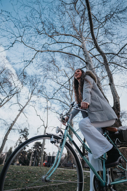 Elegante dame in zakelijke kleding op een vintage fiets neemt tijd vrij in een rustige park omgeving. - Foto, afbeelding