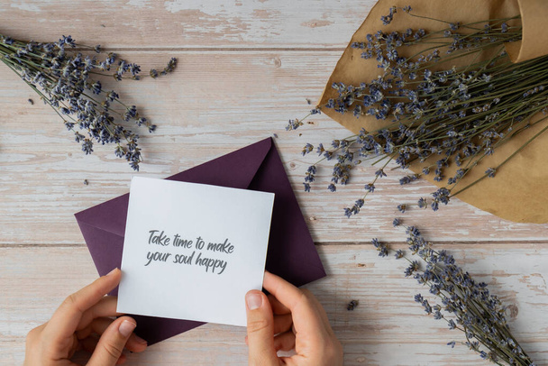 TAKE TIME TO MAKE YOUR SOUL HAPPY text on supportive message paper note reminder from green envelope. Flat lay composition dry lavender flowers. Concept of inner happiness, slowing-down digital detox - Photo, Image