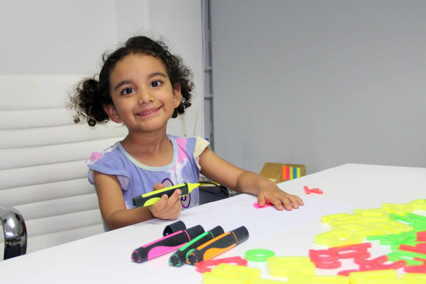 3 jaar oud Latina brunette meisje met krullend haar trekt als therapie voor autisme en aandachtstekort hyperactiviteit stoornis ADHD - Foto, afbeelding