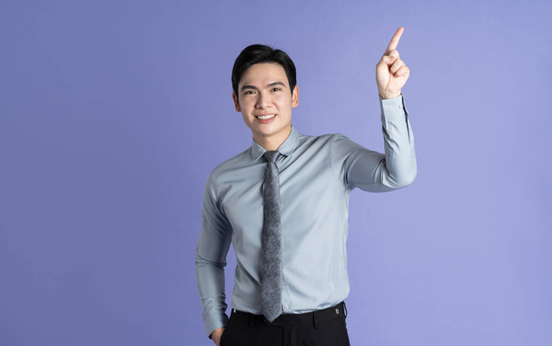Porträt eines asiatischen männlichen Geschäftsmannes, der auf lila Hintergrund posiert - Foto, Bild