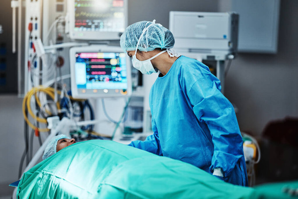 Talking, surgeon and patient in emergency surgery, professional care and hospital bed for support. Speaking, help and doctor with person in operation or mask to check healthcare in medical results. - Photo, Image