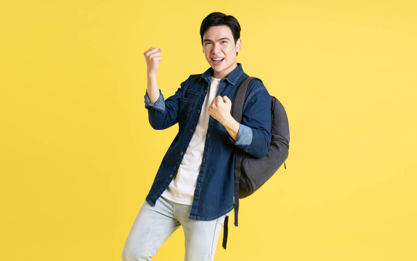 Portrét asijského studenta pózujícího na žlutém pozadí - Fotografie, Obrázek