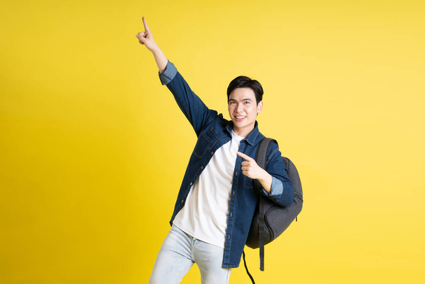 Retrato de estudiante asiático posando sobre fondo amarillo - Foto, imagen