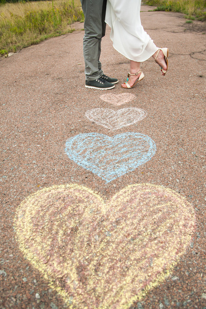 Corazón símbolos en forma de lápices de colores en el suelo y dos personas en lo
 - Foto, Imagen