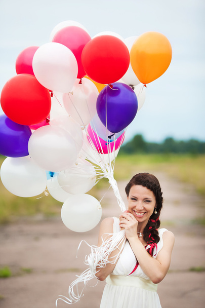 Feliz joven mujer sosteniendo en las manos coloridos globos de látex outdo
 - Foto, Imagen