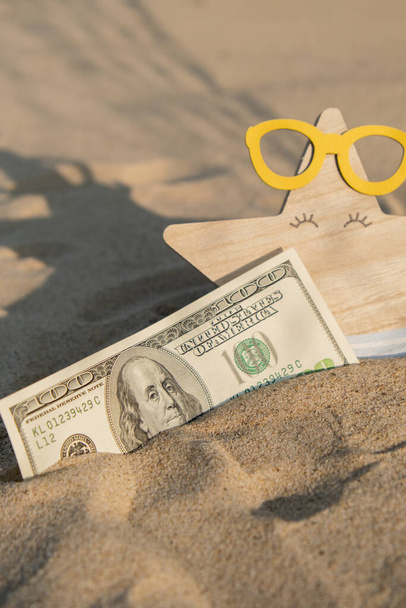 Деньги американец сто долларов купюры на песчаном пляже с морской звездой. Концепция финансирования экономии денег на каникулы. Расходы в путешествиях праздники. Тени - Фото, изображение