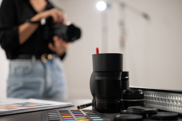 Uma imagem de close-up do equipamento de tiro profissional em uma mesa em um estúdio, uma fotógrafa trabalhando no estúdio. imagem de foco seletivo - Foto, Imagem