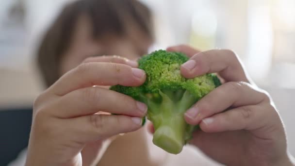 Селективный ребенок отделяет кусочки, которые он будет есть от брокколи своими руками - Кадры, видео