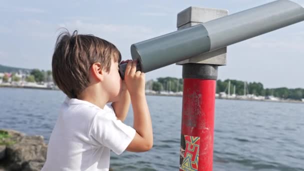 Menino observa paisagem na borda dos lagos através de telescópio público fixo durante o dia - Filmagem, Vídeo