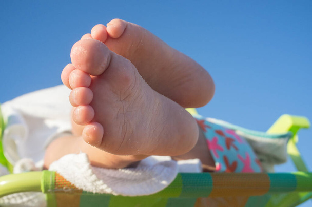 Baby boy lying over beach chair. Childrens foot health concept - Photo, Image