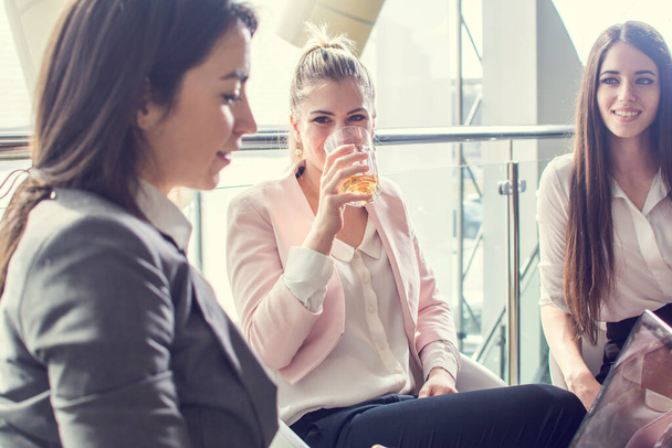 Ritratto di una bella donna d'affari che beve un drink con i suoi colleghi seduti accanto a lei in un moderno edificio per uffici - Foto, immagini