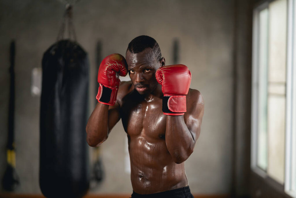 Мужчина на боксерском ринге с красной перчаткой на левой руке. Он потеет и выглядит решительным. - Фото, изображение