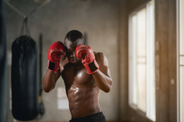 Мужчина на боксерском ринге с красной перчаткой на левой руке. Он потеет и смотрит в камеру. - Фото, изображение