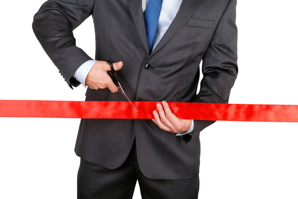Businessman in suit cutting red ribbon with pair of scissors iso - Valokuva, kuva