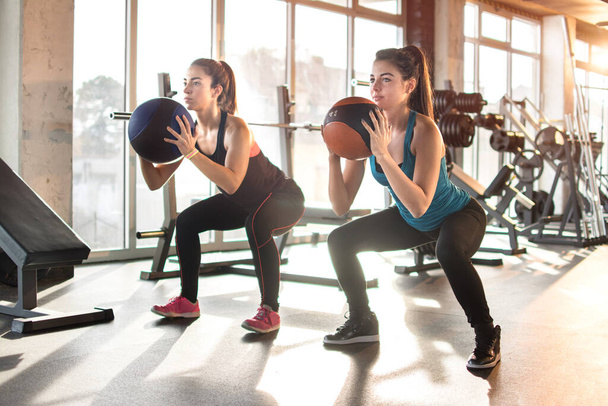 Atractivas mujeres jóvenes haciendo ejercicio con pelota de pilates en el gimnasio. - Foto, imagen