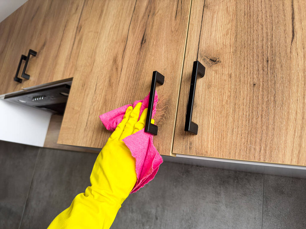fermer la femme au foyer en gant jaune laver la table en bois dans la cuisine. Assainissement, nettoyage de maison - Photo, image