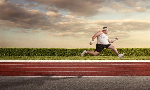 Funny overweight man speeding on the running track with copy spa - Photo, Image