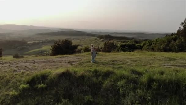Mladá fotografka pózuje na pozadí západu slunce na krásném místě v lese. Střelba z 4K dronu - Záběry, video